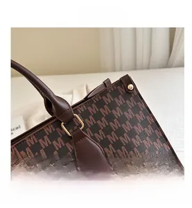 Detail showing high-quality stitching on brown monogram tote bag with gold metal buckle