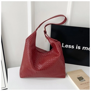 Macro detail of wine red woven leather hobo bag featuring golden zipper and luxury texture