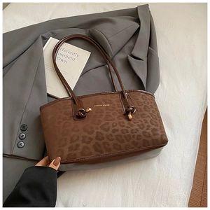 Dettaglio della borsa tote leopardata con logo in metallo su sfondo blazer grigio elegante