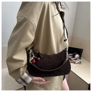 Détail du sac demi-lune en daim marron foncé avec charm cerise et chaîne dorée