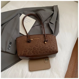 Dettaglio della borsa tote leopardata con finiture in pelle marrone e scritte dorate