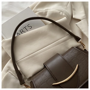 Detail of dark brown faux crocodile leather shoulder bag with golden crescent buckle