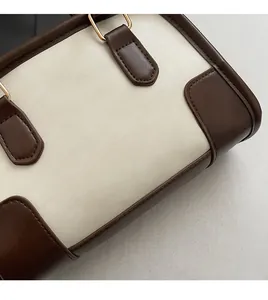 Detail view of the bicolor faux leather pillow bag with elegant gold logo printing
