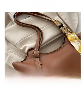Detail of brown leather hobo bag featuring decorative floral silk scarf and metal buckle