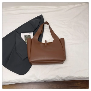 Dettaglio di una borsa tote in pelle PU marrone con manici lunghi e fibbia decorativa
