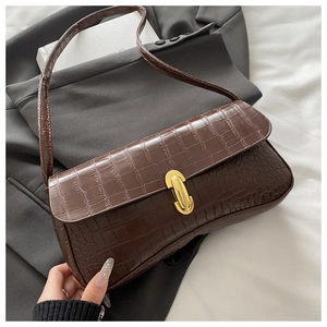 Detail of a brown faux-crocodile texture baguette bag with a sleek gold metal buckle