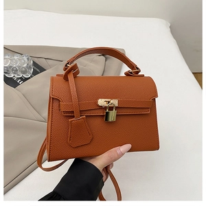 Detail of caramel brown pebble leather tote bag featuring metal lock and top handle
