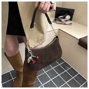 Detail of brown suede hobo bag with gold chain strap and cute cherry charm accessory