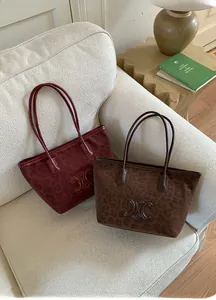 Close-up of leopard print tote bags in deep red and brown with embossed logo