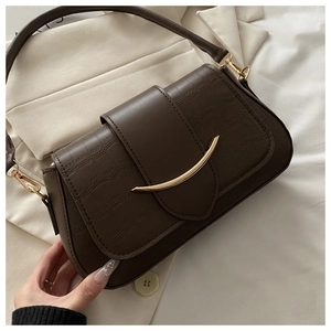 Detail of dark brown crocodile embossed crossbody bag with golden crescent clasp