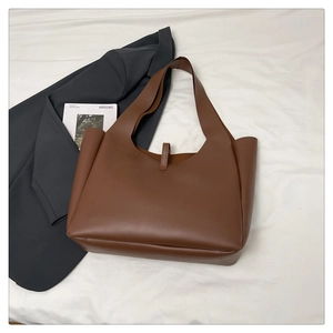 Grande borsa tote marrone scuro minimalista su panno bianco con blazer grigio