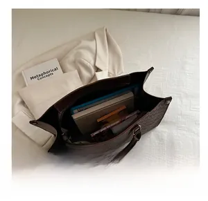 Top view of spacious brown monogram tote bag interior showing books and laptop space