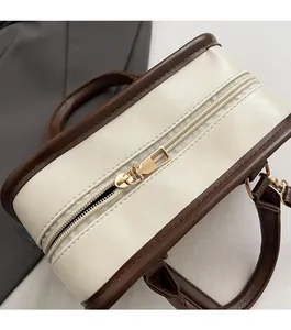 Detail of premium dual golden metal zippers on a vintage cream and brown handbag