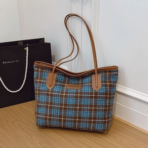 Grand sac cabas à carreaux bleu et marron avec anses en cuir dans un décor élégant