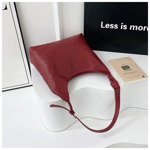 Detail of burgundy textured leather hobo bag with adjustable strap on white stand