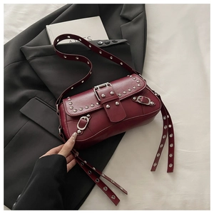 Dettaglio borsa sottobraccio bordeaux con rivetti, tracolla con occhielli e stile Y2K