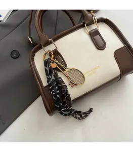 Detail of two-tone boston bag featuring tennis racket pendant and fashion text print