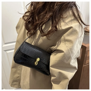 Black crocodile embossed underarm bag with gold metal buckle shown on shoulder
