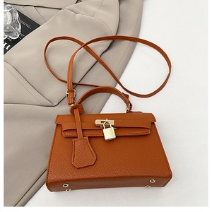 Detail of brown litchi pattern leather handbag with gold padlock on a khaki blazer