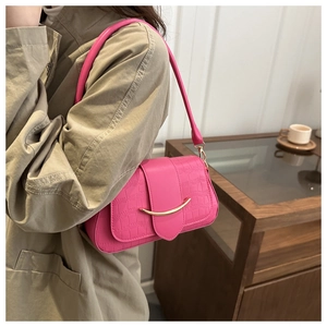 Pink embossed faux-crocodile shoulder bag with gold crescent hardware on model