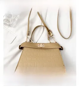 Detailansicht der Khaki-Krokodilprägung und des Metalldrehverschlusses an der Tasche