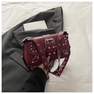 Dettaglio dei rivetti argentati e degli occhielli in metallo su borsa in pelle bordeaux