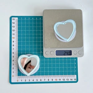 Macro view of blue heart-shaped mirror phone stand weighing approximately 24 grams