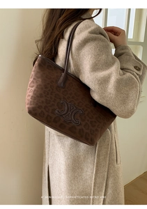 Close-up of leopard print suede tote bag featuring a retro brown logo and shoulder strap