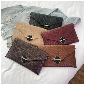Detailed view of colorful woven envelope bags with metal buckles and gold chain straps