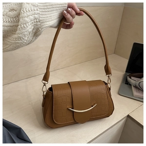 Detail of brown crocodile pattern shoulder bag with a gold crescent metal clasp