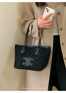 Close-up of black leopard print tote bag with leather logo patch and slim shoulder straps