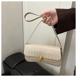 Close-up of cream crocodile pattern textured handbag with gold metal twist lock