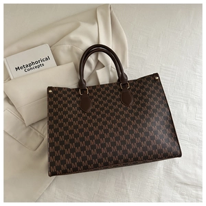 Macro shot of brown monogram tote bag with leather straps and structured vintage pattern