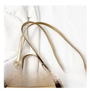 Detailansicht der goldfarbenen Lederhandtasche mit verstellbarem Gurt und Metallverschluss