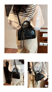 Detail view of black leather pillow bag featuring striped tassel and gold foil branding