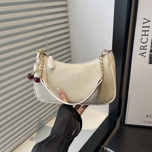 Sac bandoulière beige chic avec chaîne dorée et pendentif cerise rouge élégant