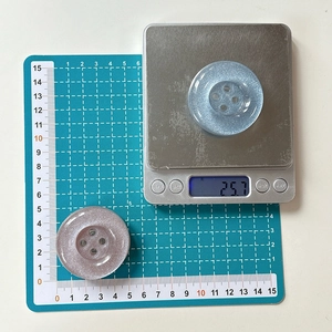 Glittering button phone grip showing a 4.5cm diameter on a green cutting mat scale