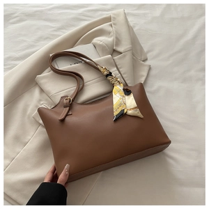 Close-up of brown matte leather tote bag handle featuring a printed decorative silk scarf