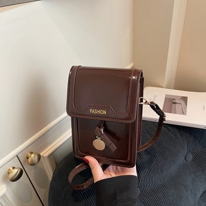 Fashionable dark brown crossbody bag in glossy faux leather with gold pendant and knot detail