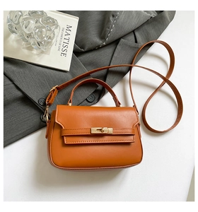 Vue détaillée d'un sac à main orange-brun avec fermoir tournant en métal et blazer gris