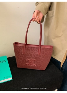 Close-up of leopard print tote bag featuring a retro red finish and embossed metal buckle