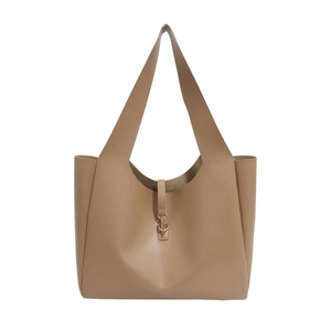 Minimalist warm brown leather tote bag with wide shoulder strap and metal hook closure