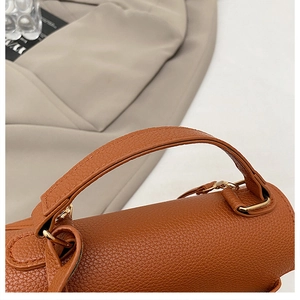 Detail of brown lychee grain leather handbag with gold metal ring hardware