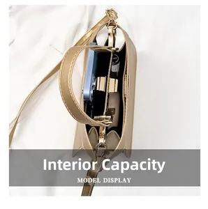 Draufsicht auf das Innenfach der goldenen Kelly-Handtasche mit einem Smartphone darin
