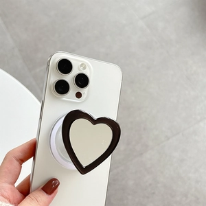 Detail of heart-shaped magnetic phone grip with silver mirror and black frame on white iPhone