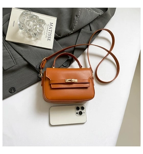 Détail d'un sac à main caramel avec fermoir doré et smartphone pour référence de taille