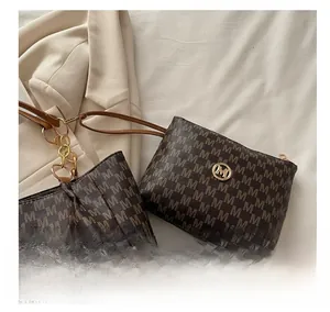 Close-up of brown faux leather mini pouch with M-pattern print and golden logo charm