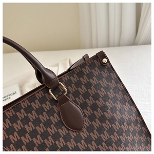 Detail of vintage brown tote bag with letter M print and gold metallic hardware