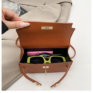 Detail view of brown lychee leather handbag interior showing wallet and sunglasses