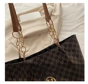 Detail view of coffee tote bag with M monogram print and gold chain strap hardware